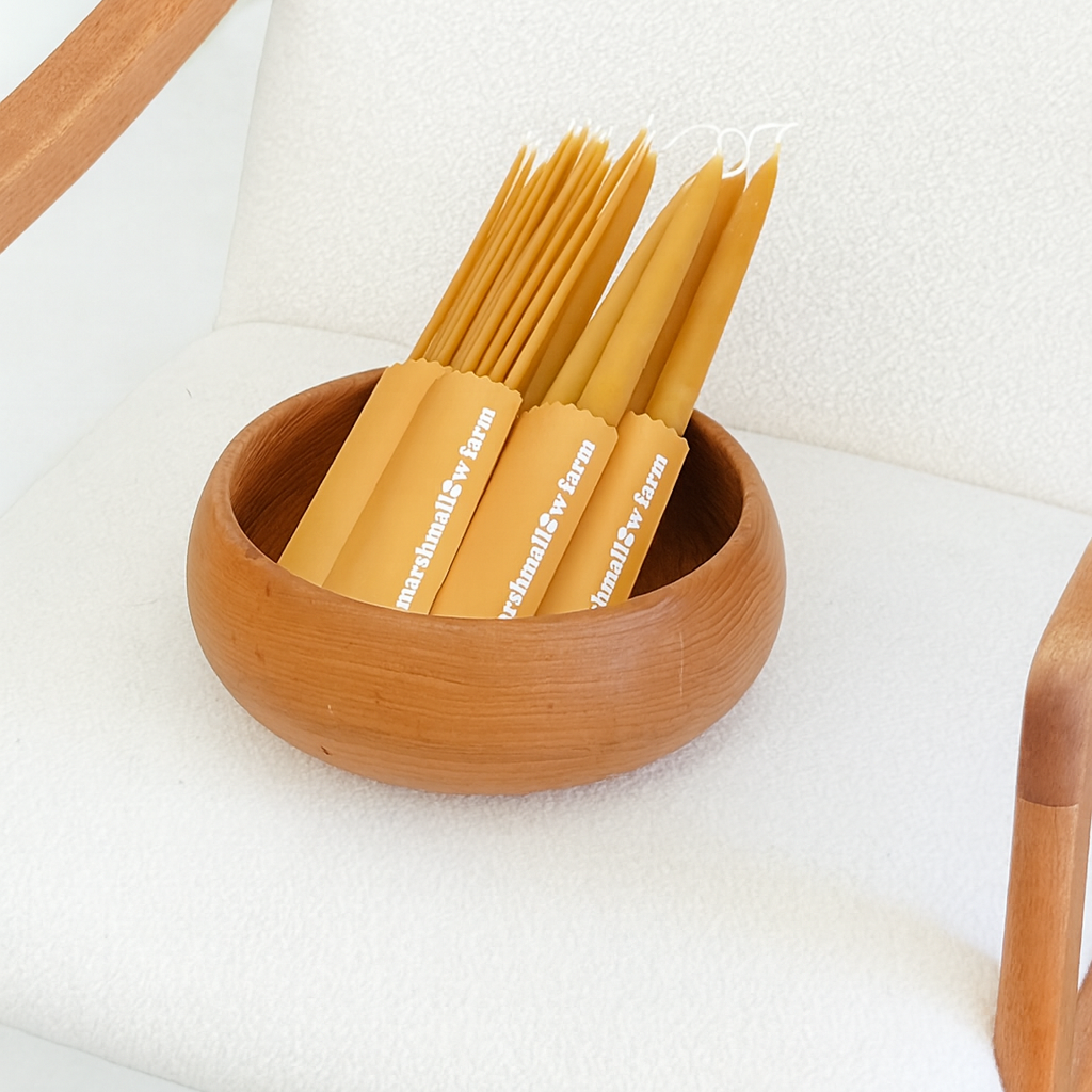 Beeswax taper candles in yellow packaging.