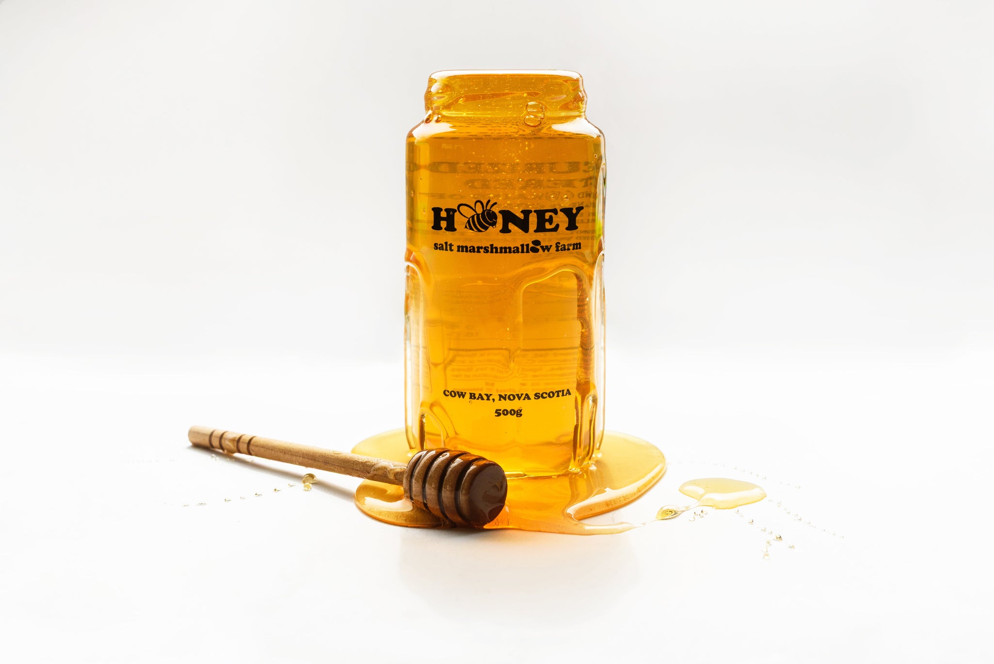 Jar of honey with a wooden dipper on a white background
