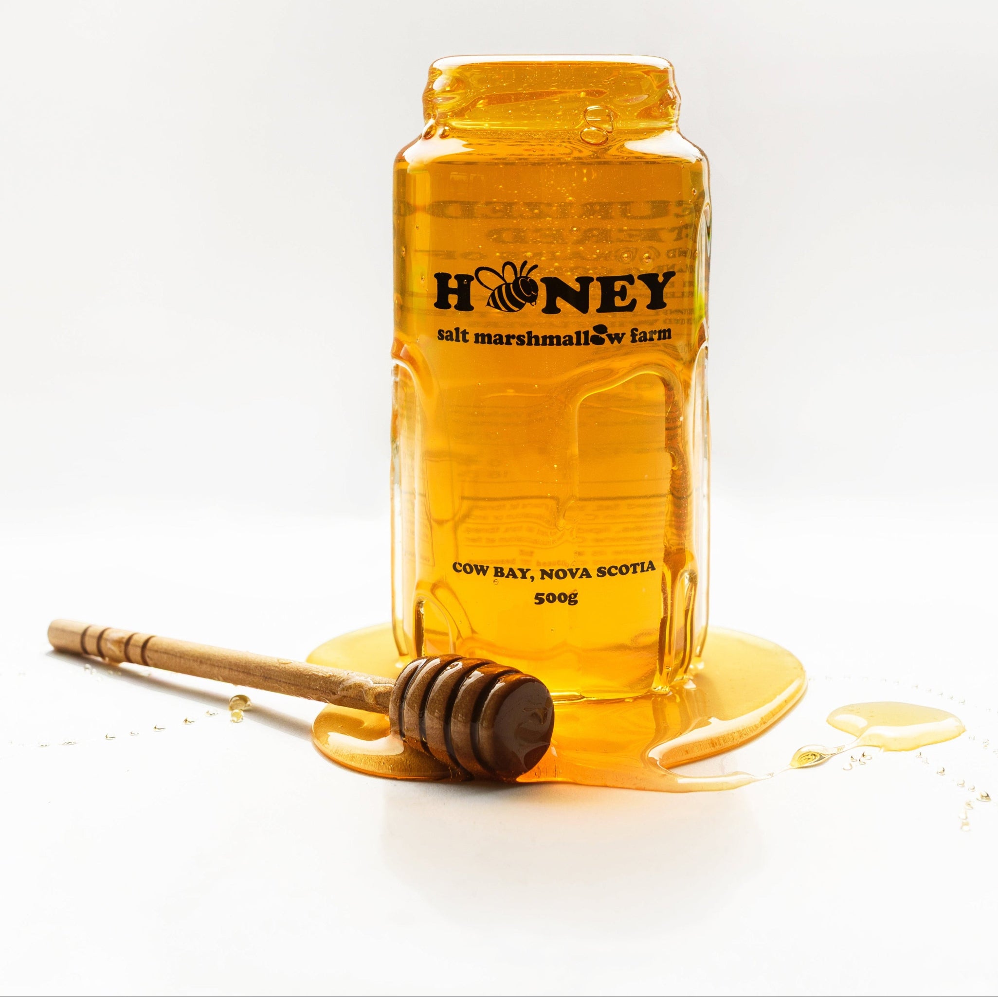 Jar of honey with a honey dipper on a white background